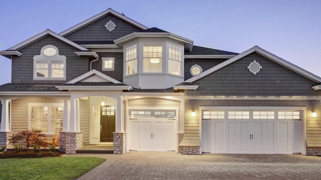Grey-sided family home with white trim lit up at dusk